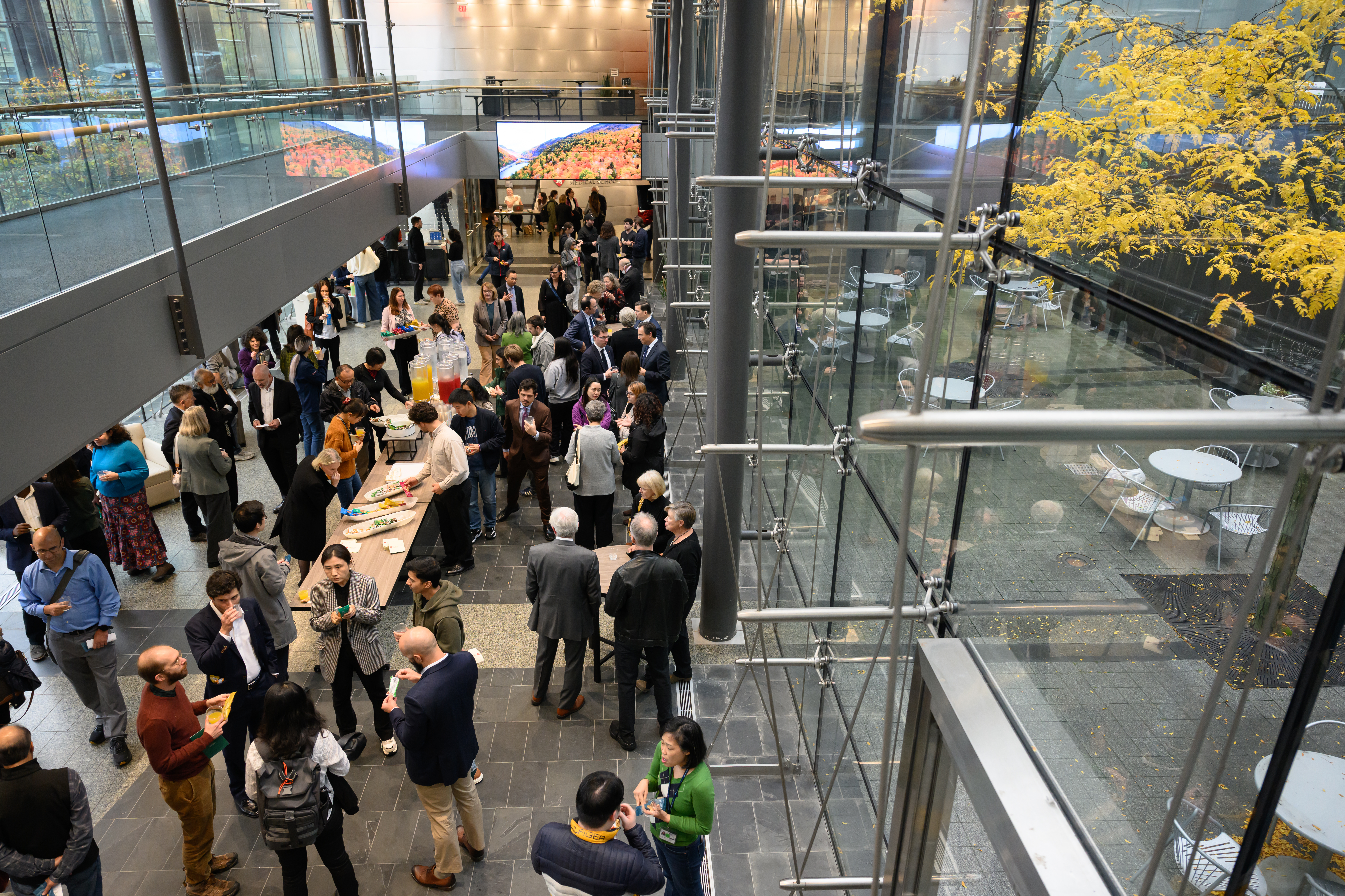 Group of people standing around a lobby where there are tables of food.